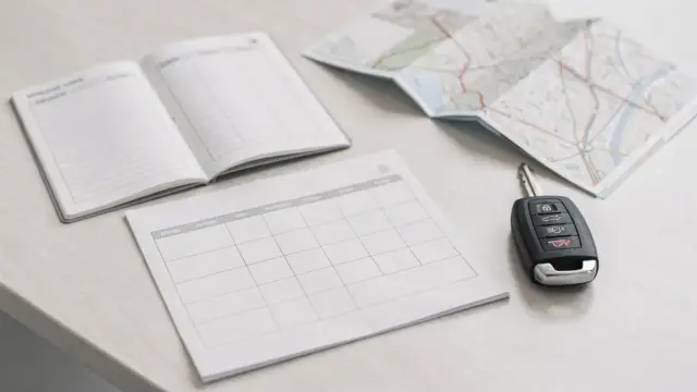 Unterlagen zu betrieblichen Fahrten mit Fahrtenbuch, Schlüssel und Kalender auf dem Schreibtisch
