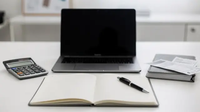 Schreibtisch mit Laptop, Taschenrechner und Belegen zu den Kosten der Selbstständigkeit