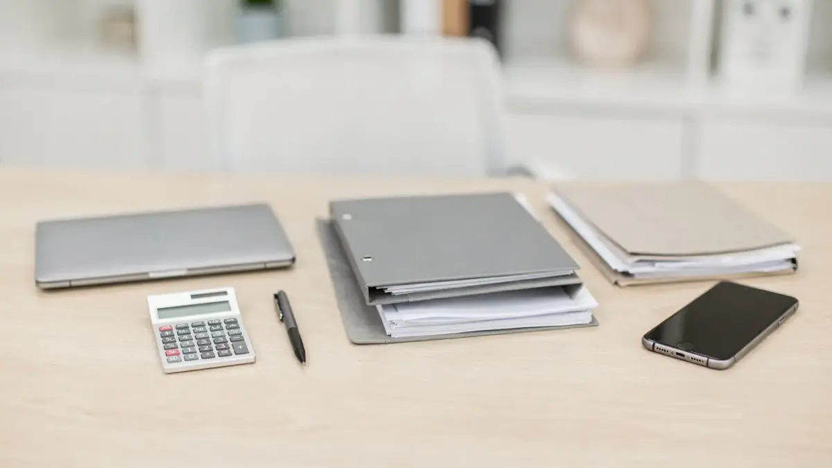 Büro-Setup mit Laptop, Rechner und Unterlagen zur privaten Absicherung für Selbstständige